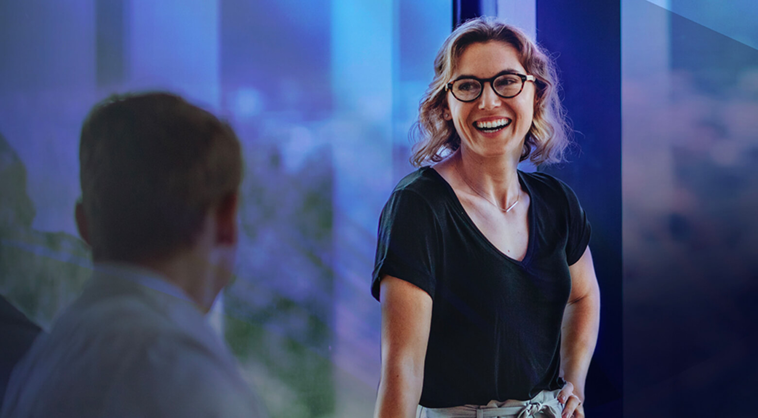 A woman in business attire laughing in a meeting.